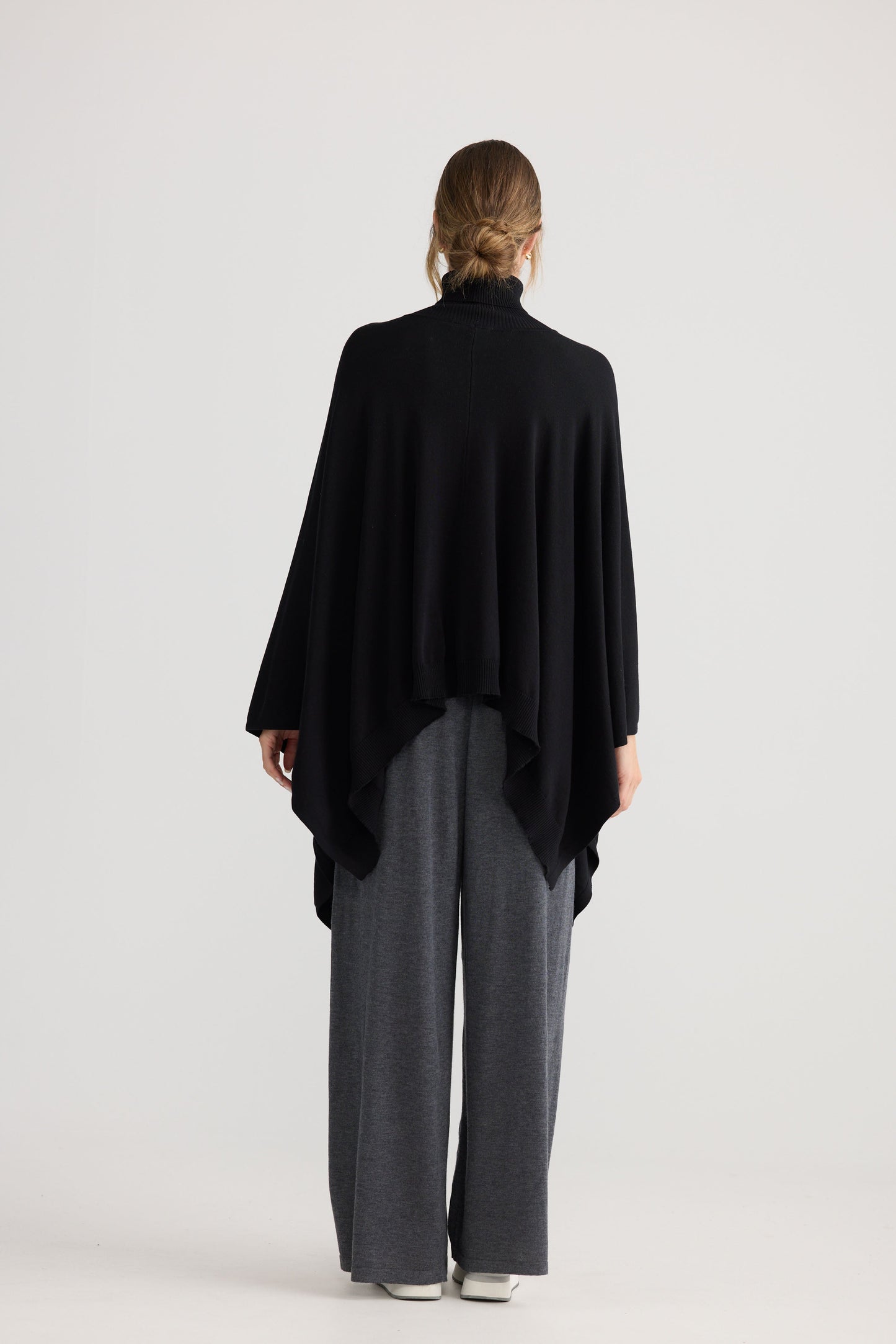 Awaken Knit Cape in black, styled with a relaxed outfit.