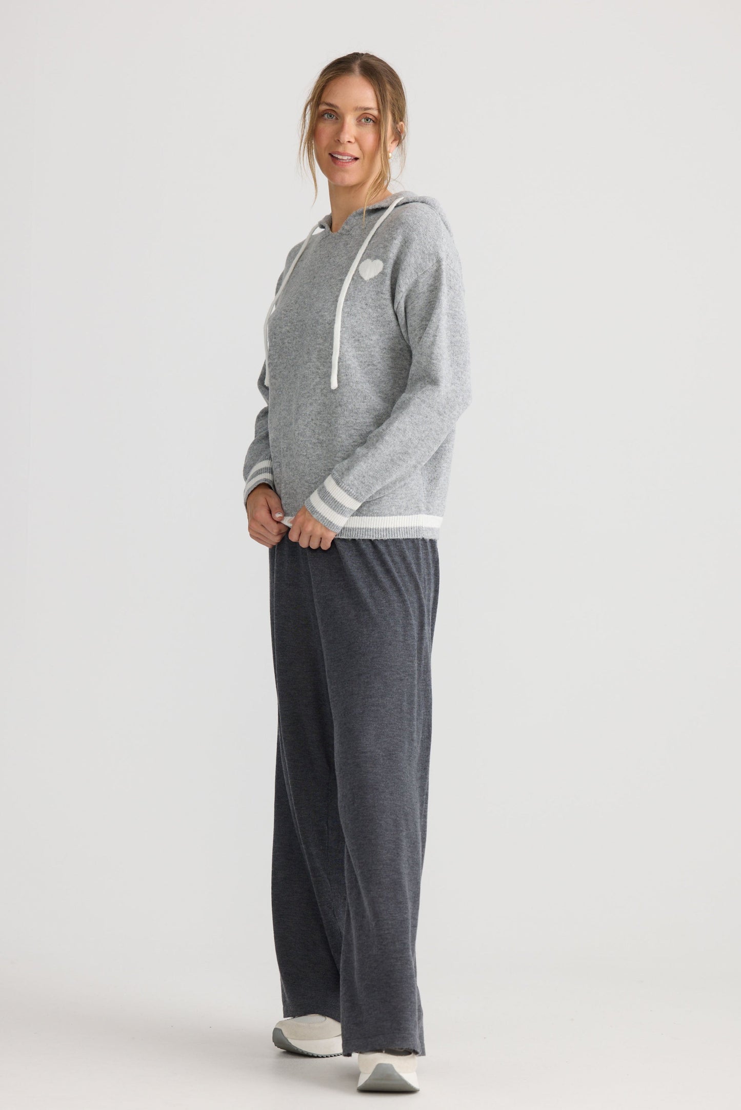Model wearing Bold Hearts Hoodie in grey, showing hooded knit shape.